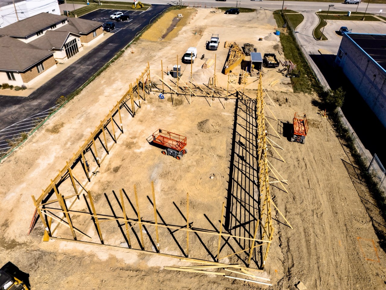Aerial view of the framed perimeter walls at Apex Strength Club with roof trusses staged beside the building