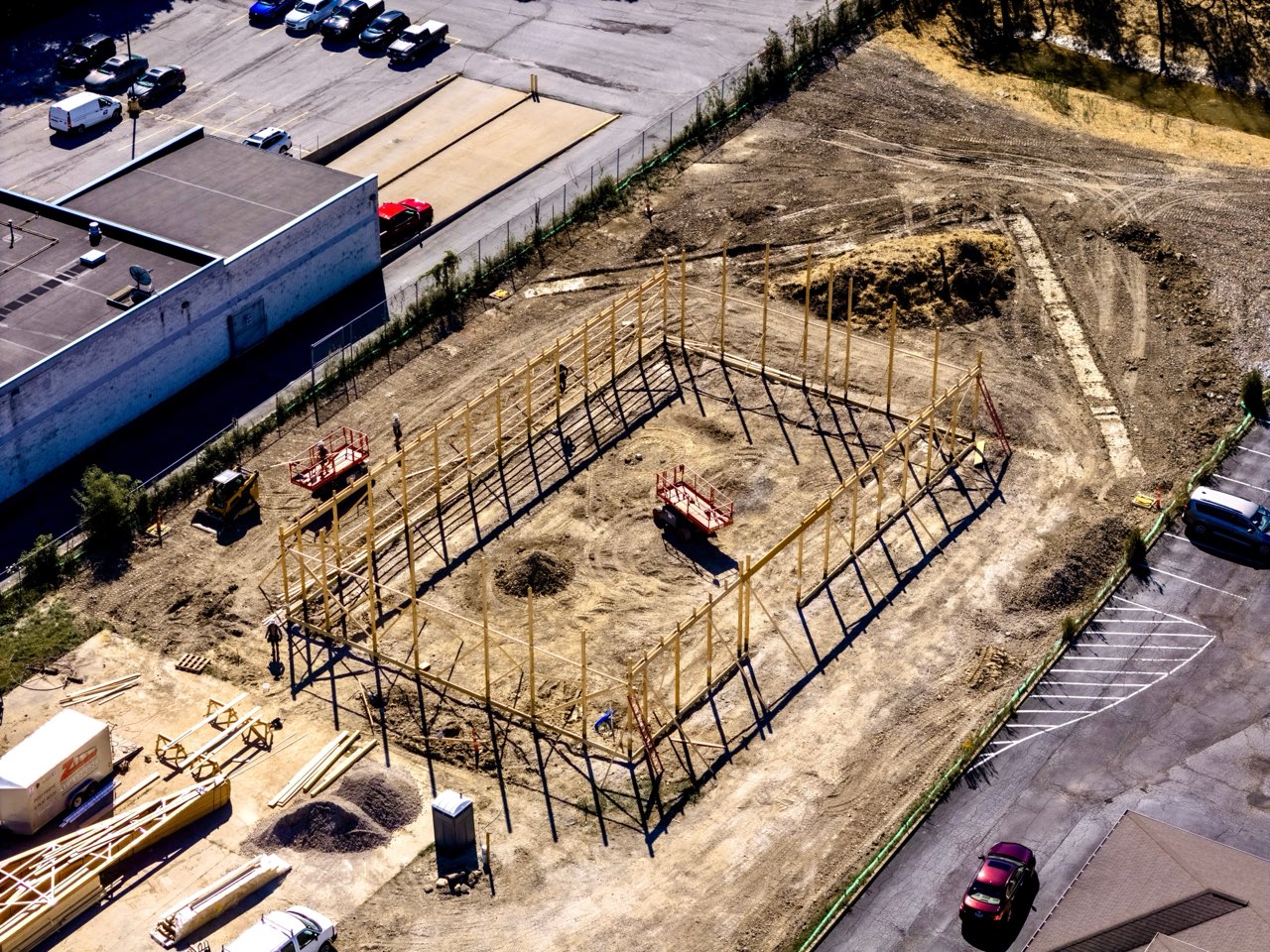 Aerial view of the Apex Strength Club building footprint framed out with lumber and trusses stacked nearby